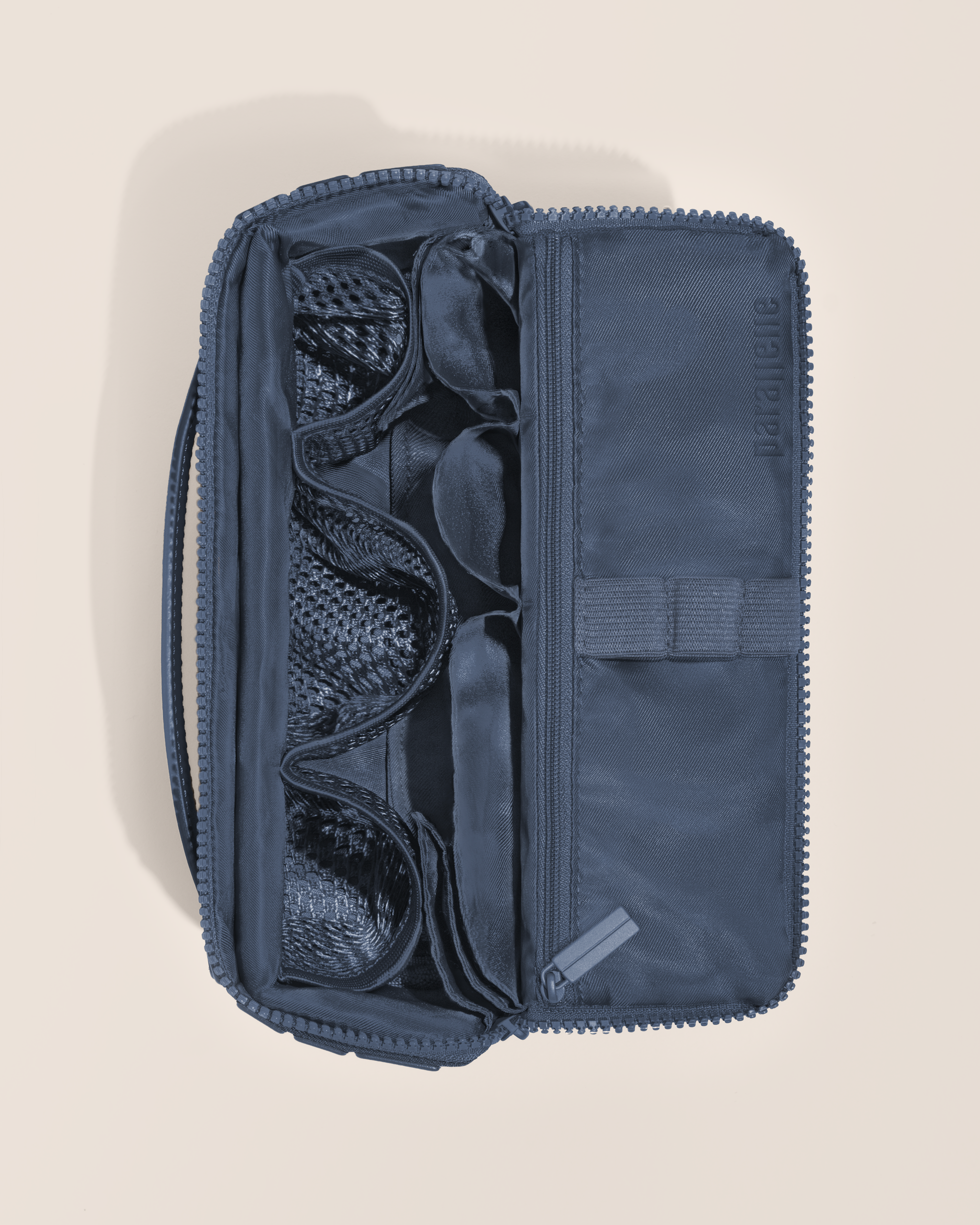 Overhead view of Parallelle Medium Indigo (blue) Kit toiletry bag, showcasing its structured interior with multiple compartments and mesh pockets for organized travel storage
