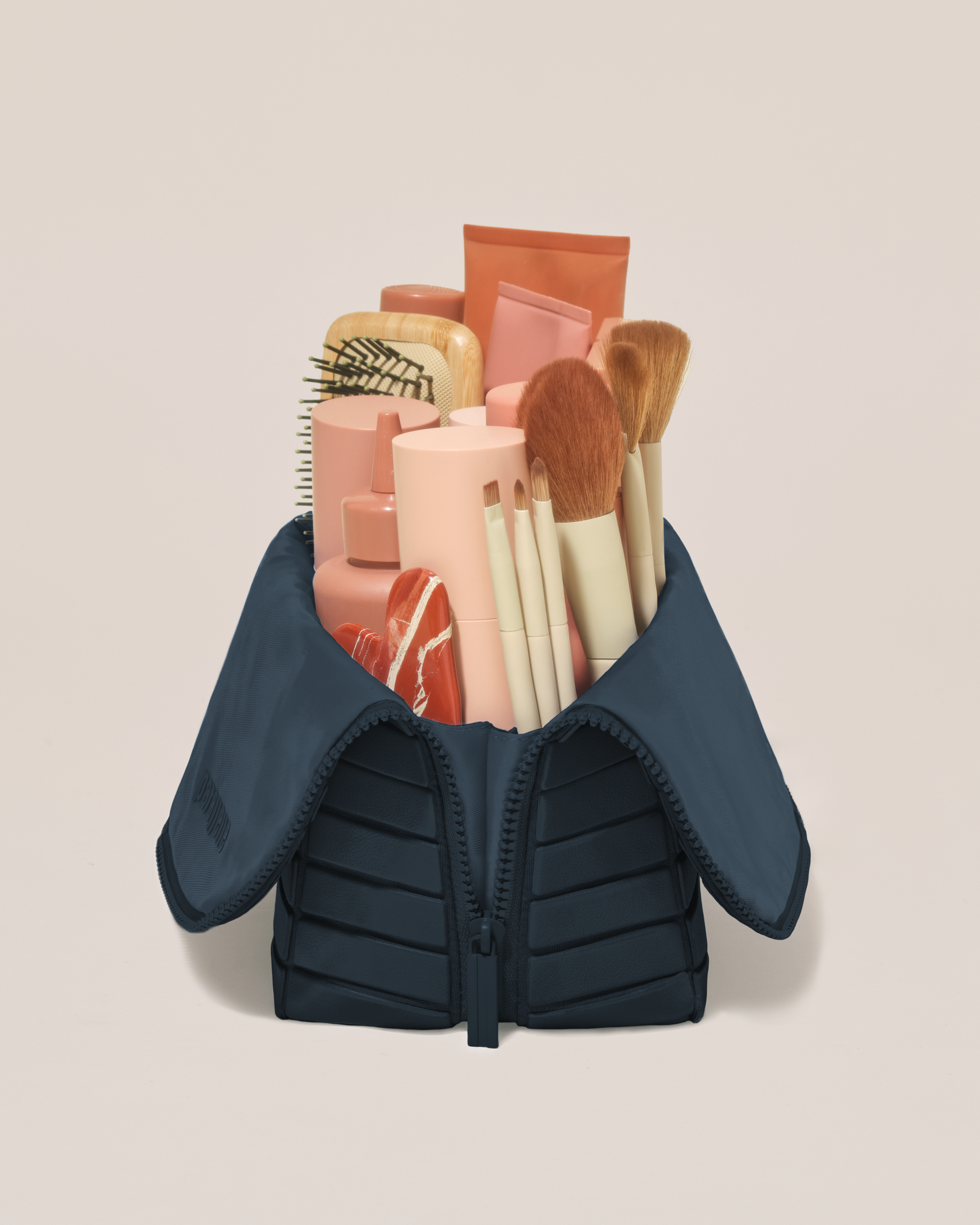 Side profile of the Large Indigo (navy) Traveller makeup bag filled with beauty essentials standing upright, showing flexible compartment design