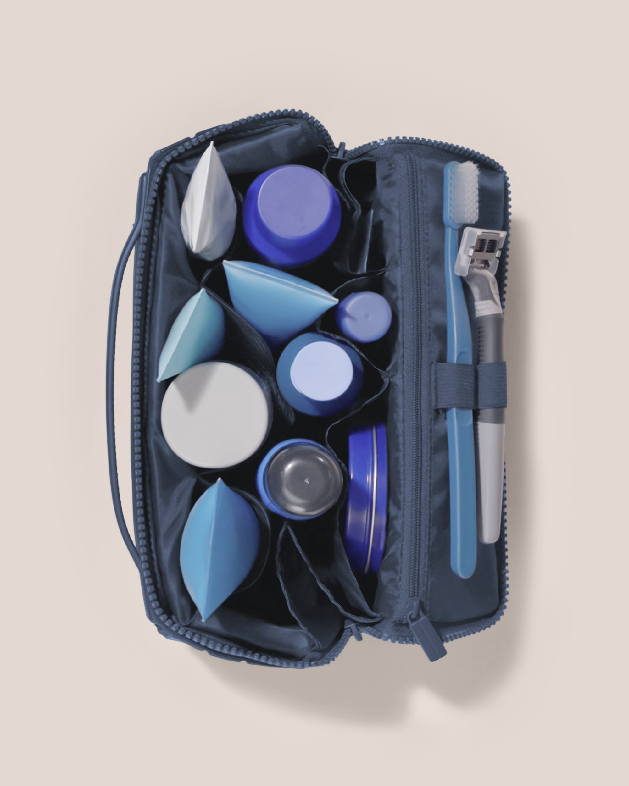 Overhead view of Parallelle Medium Indigo (blue) Kit toiletry bag fully packed with upright toiletry products and organized compartments