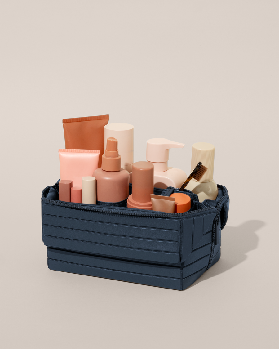 Open Parallelle Indigo (blue) Kit, shown open and packed with skincare and grooming products. A compact, structured toiletry bag designed for visibility and access