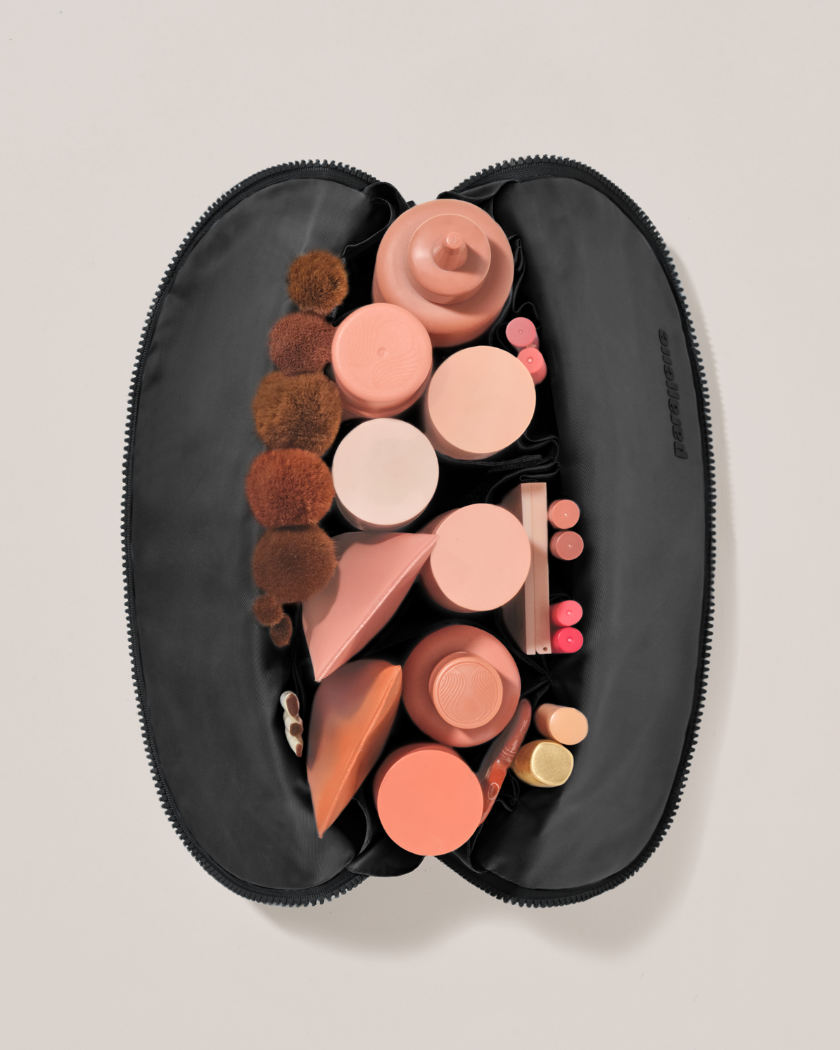 Overhead view of the Large Onyx (black) Traveller makeup bag fully packed with upright beauty products and organized compartments