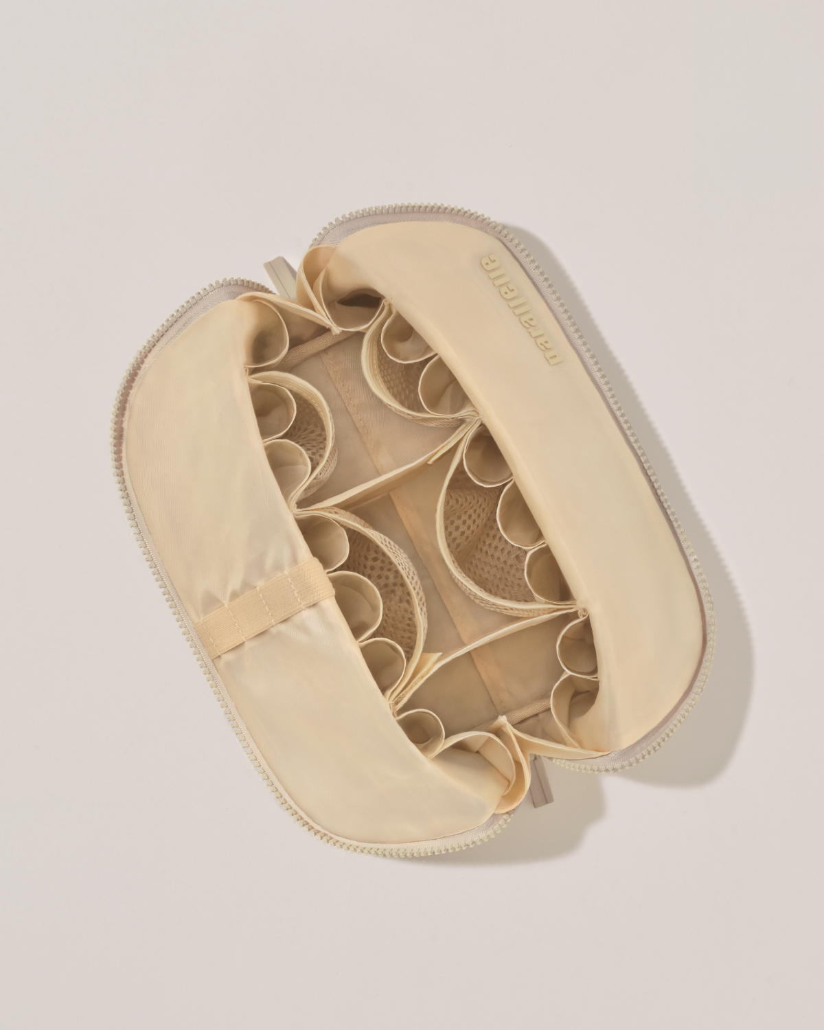Interior view of Parallelle Medium Bisque (white) Traveller makeup bag showing empty pockets, pouches, and elastic holders