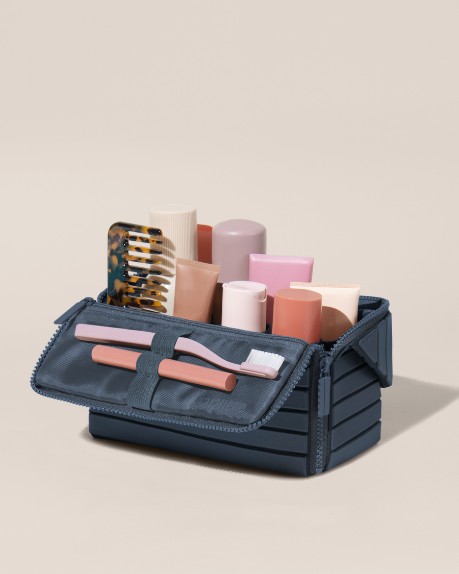 Open Parallelle Medum Indigo (blue) Kit, shown open and packed with skincare and grooming products. A compact, structured toiletry bag designed for visibility and access.