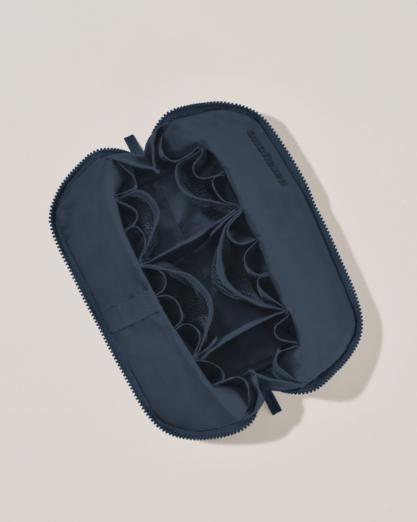 Interior view of Parallelle Medium Indigo (navy) Traveller makeup bag showing empty pockets, pouches, and elastic holders