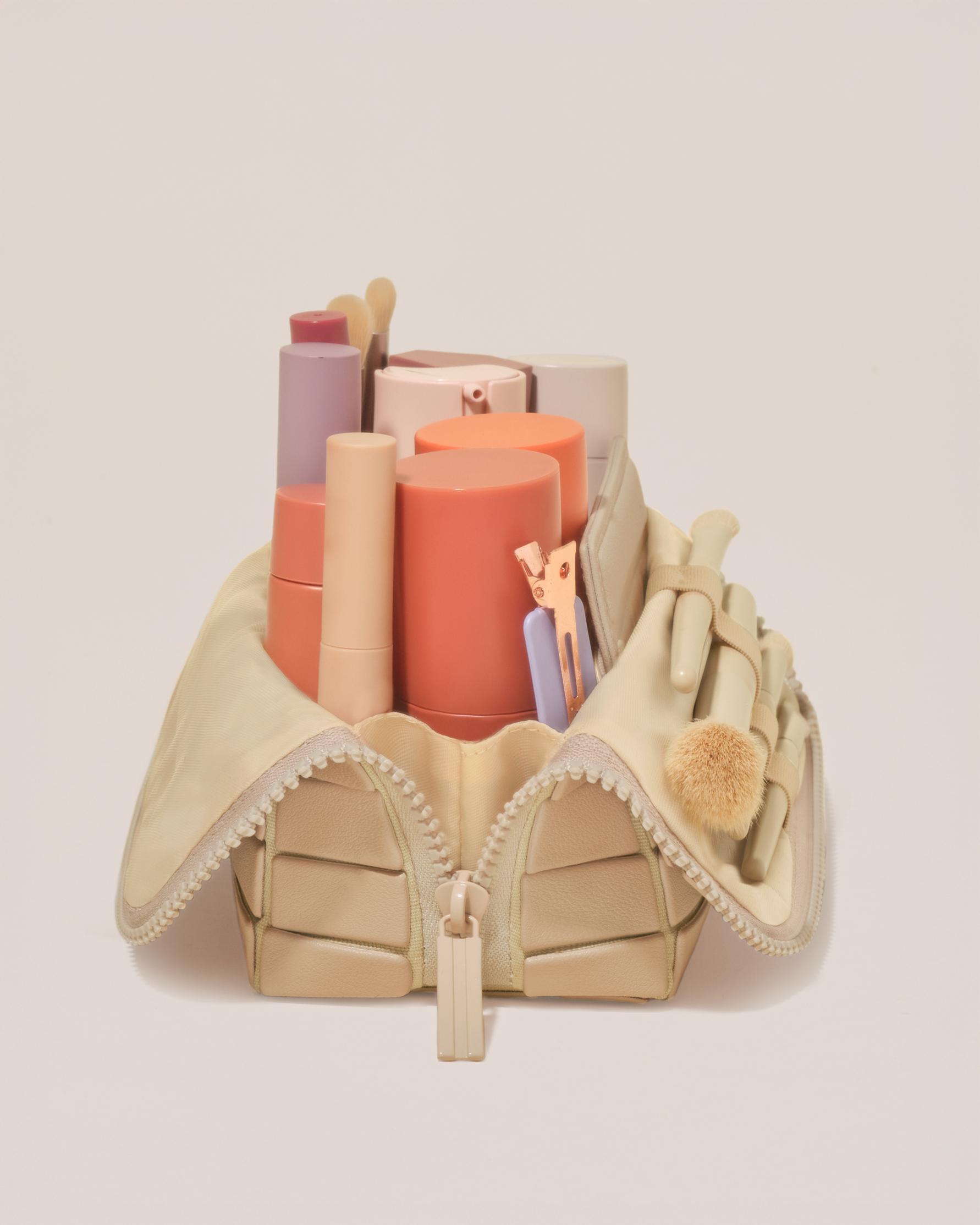 Side profile of the Small Bisque (white) Traveller makeup bag filled with beauty essentials standing upright, showing flexible compartment design